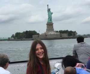 Student smiling with the Statue of Liberty in the background