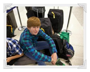 Kid sitting on the floor next to suitcases at the airport