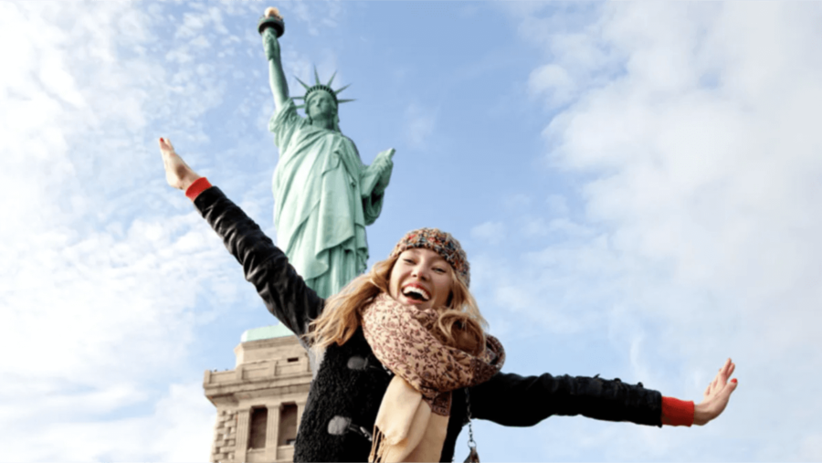 Teen girl smiling and posing in front of the Statue of Liberty