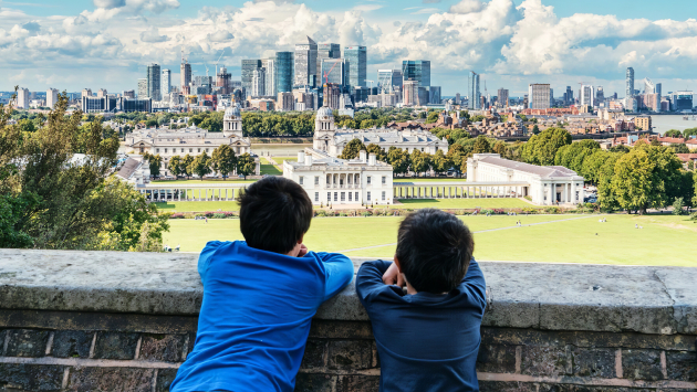 Young students leaning their chins on a wall looking out at a city