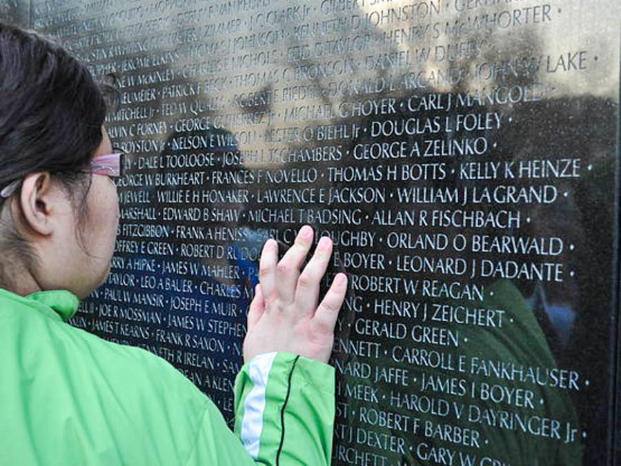 Student touching monument with names etched into it.