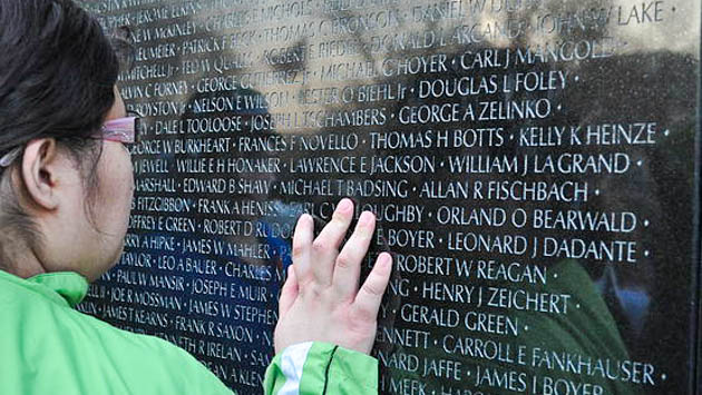 Student touching monument with names etched into it.