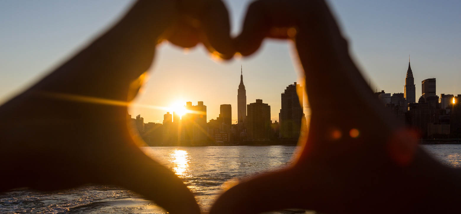 Hands making a heart with the NYC skyline in the middle