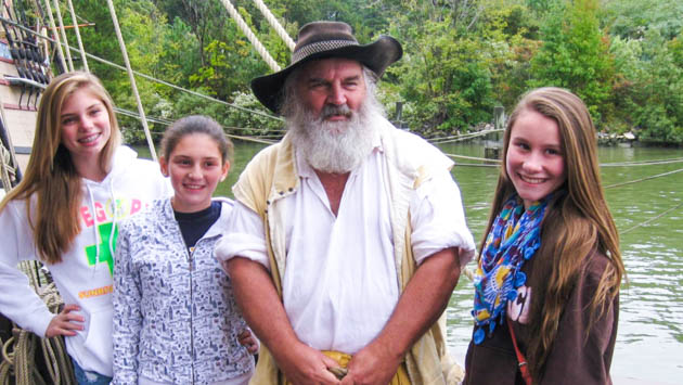 Three students with a colonial reenactor