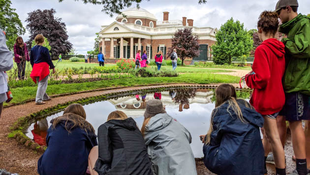 Students crouching by a pond outside of Monticello