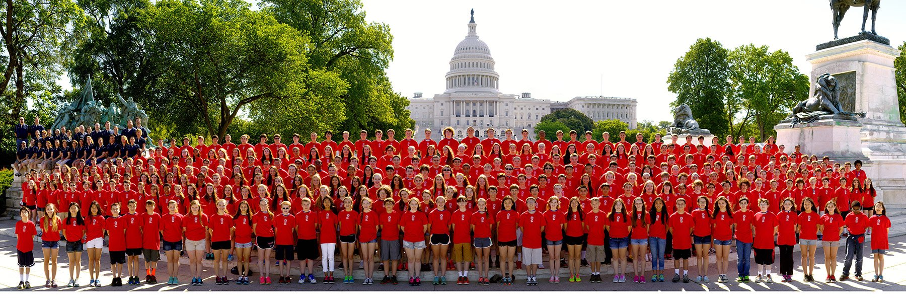 Large tour group all in red shirts taking a group photo outside of the capitol building