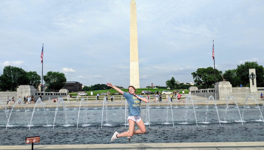 Girl jumping in the air in front of the Washington monument