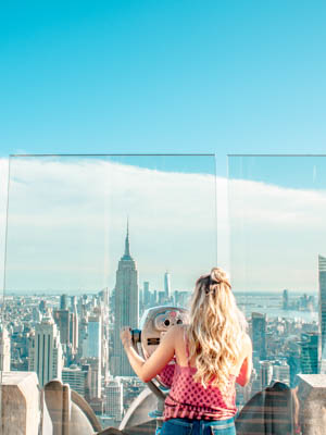 Girl looking through a telescope at the NYC skyline