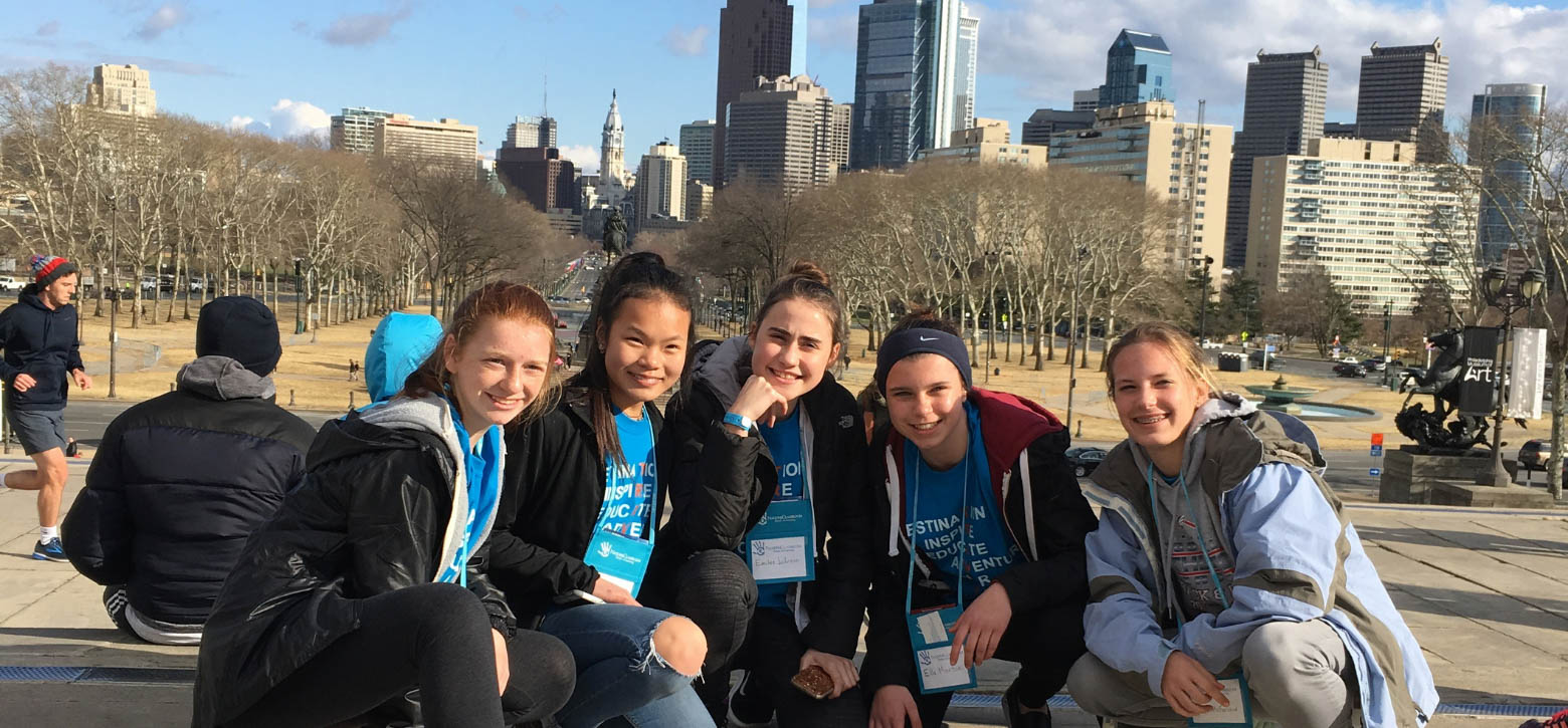 Group of students taking a photo with the NYC skyline in the background