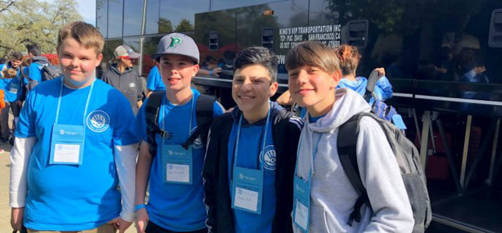 Group of four boys in front of a tour bus