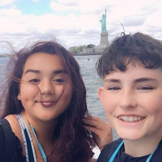 young boy and girl posing with The Status of Liberty in the background