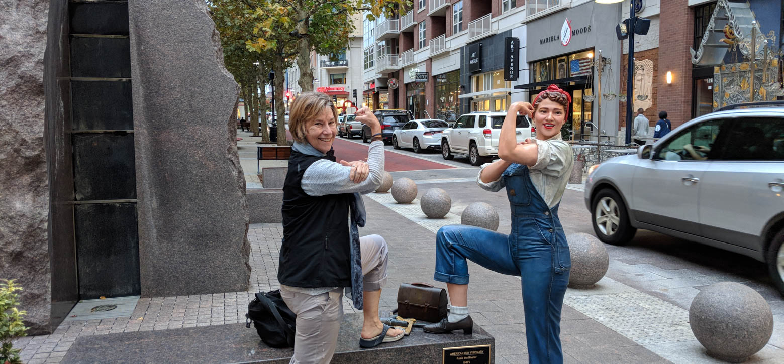 Teacher flexing her bicep with Rosie the Riveter Statue