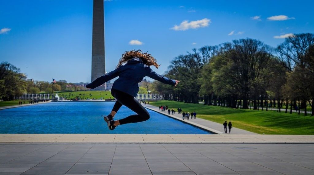 student jumping in front of the Washington Monument