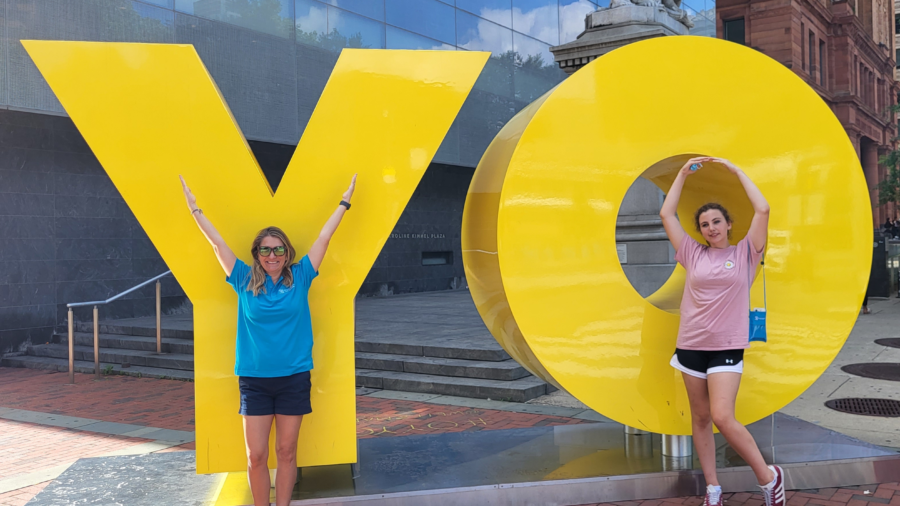 Student and teacher standing in front of yellow sign